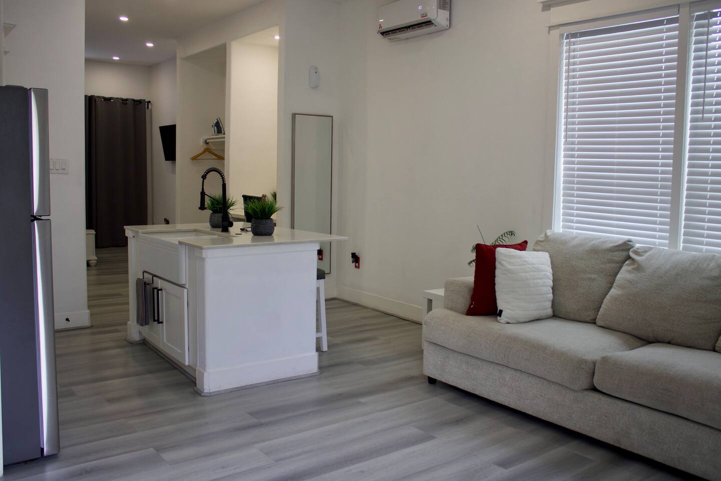 Unit 3 living room with a sofa beside a kitchen island and window blinds
